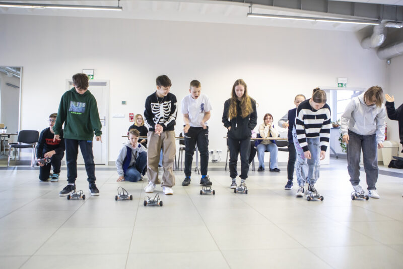 Grupa dzieci przeprowadza zawody robotów zbudowanych podczas warsztatów w Kopalni Ignacy.