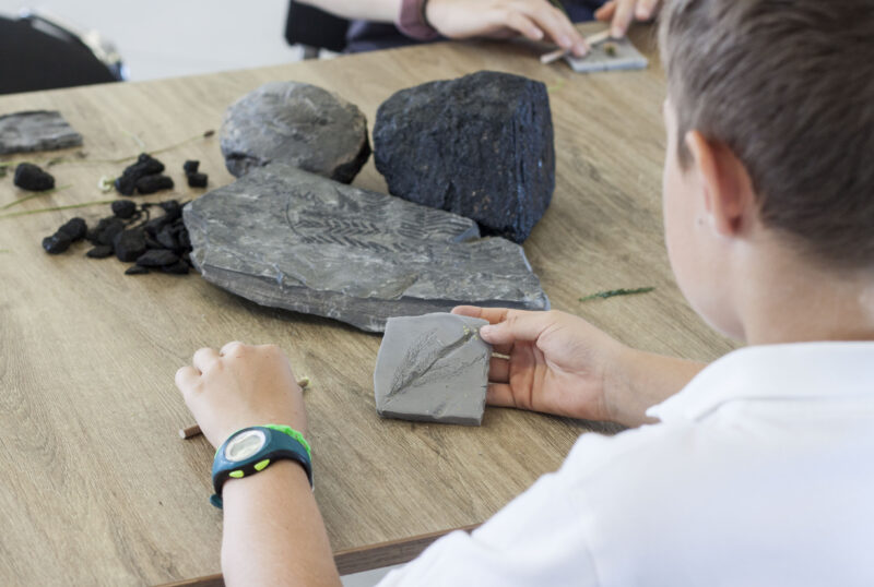 Chłopiec siedzi przy bryłkach węgla i obserwuje je podczas zajęć w Zabytkowej Kopalni Ignacy w Rybniku